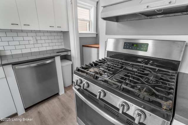 4015 S 5th St, Louisville, KY 40214 - kitchen with stainless steel appliances, dark countertops, under cabinet range hood, white cabinets, and light wood-type flooring