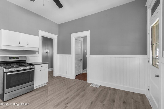 4015 S 5th St, Louisville, KY 40214 - kitchen featuring gas stove, under cabinet range hood, a wainscoted wall, a ceiling fan, and white cabinets