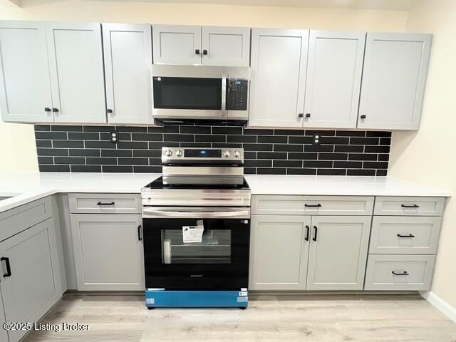 7402 Nottoway Cir, Louisville, KY 40214 - kitchen featuring appliances with stainless steel finishes, light wood finished floors, tasteful backsplash, and light countertops