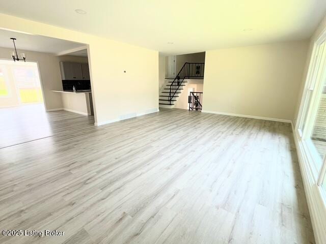 7402 Nottoway Cir, Louisville, KY 40214 - unfurnished living room with wood finished floors, plenty of natural light, stairs, and a chandelier