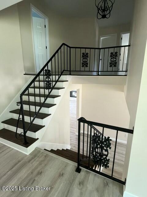 7402 Nottoway Cir, Louisville, KY 40214 - stairway featuring wood finished floors, a high ceiling, and a chandelier