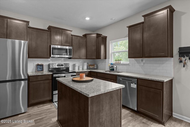 1105 Johnson Ridge Rd, Louisville, KY 40245 - kitchen featuring stainless steel appliances, a sink, dark brown cabinetry, light wood-style flooring, and a kitchen island
