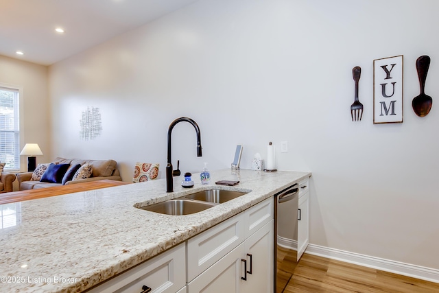 421 Marret Ave, Louisville, KY 40208 - kitchen featuring a sink, dishwasher, light wood-style flooring, light stone countertops, and baseboards