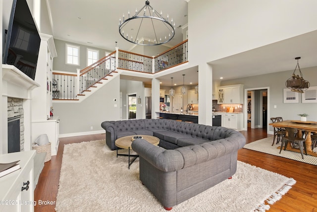7811 Ingram Way, Crestwood, KY 40014 - living area with a chandelier, a towering ceiling, wood finished floors, a stone fireplace, and stairs