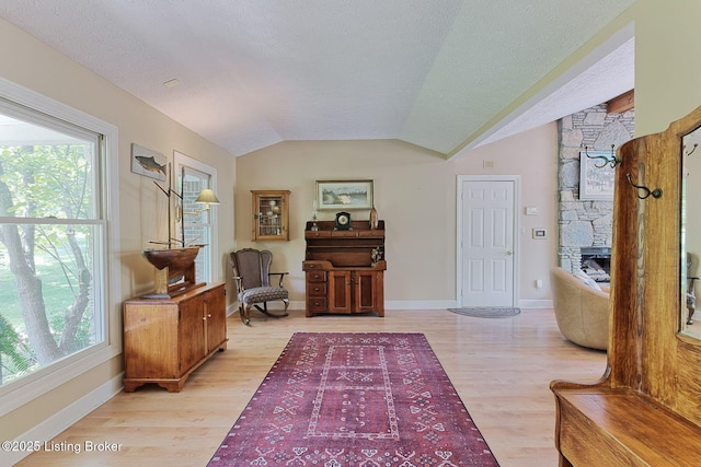 6311 Fible Ln, Crestwood, KY 40014 - living area with light wood-type flooring, healthy amount of natural light, a stone fireplace, lofted ceiling, and a textured ceiling