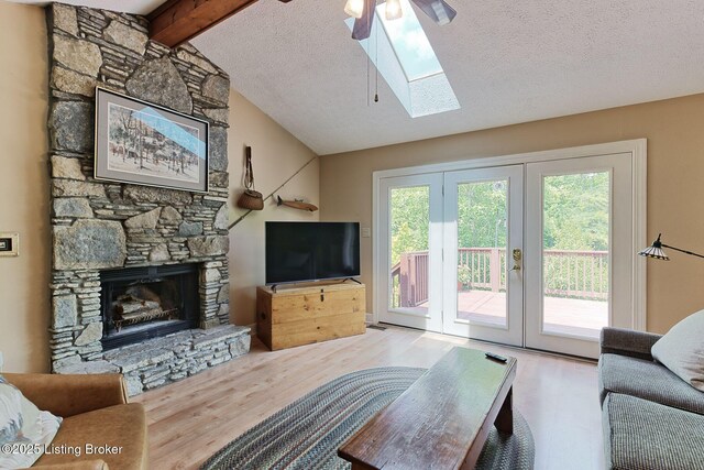 6311 Fible Ln, Crestwood, KY 40014 - living room featuring a skylight, wood finished floors, a stone fireplace, ceiling fan, and french doors