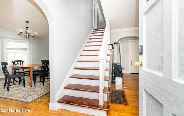 4825 Manslick Rd, Louisville, KY 40216 - staircase featuring arched walkways, a chandelier, wood finished floors, crown molding, and baseboards