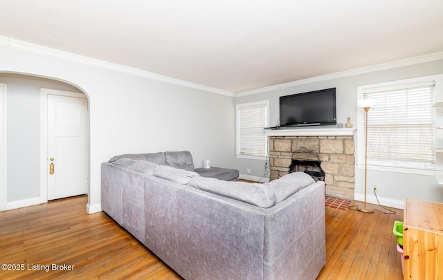 4825 Manslick Rd, Louisville, KY 40216 - living area with wood-type flooring, baseboards, crown molding, arched walkways, and a stone fireplace