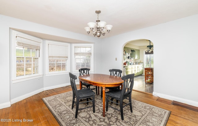 4825 Manslick Rd, Louisville, KY 40216 - dining area with a chandelier, baseboards, arched walkways, and wood finished floors