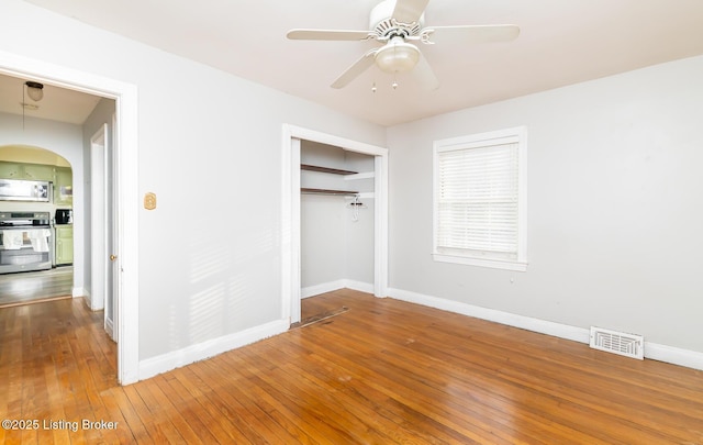 4825 Manslick Rd, Louisville, KY 40216 - unfurnished bedroom featuring baseboards, arched walkways, hardwood / wood-style flooring, a closet, and ceiling fan