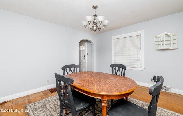 4825 Manslick Rd, Louisville, KY 40216 - dining space featuring arched walkways, a chandelier, baseboards, and light wood-type flooring