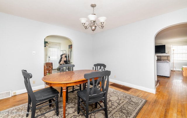 4825 Manslick Rd, Louisville, KY 40216 - dining room with arched walkways, light wood-style floors, a chandelier, and baseboards