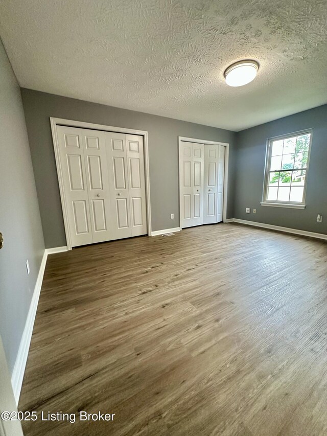 512 Auburn Oaks Dr, Louisville, KY 40214 - unfurnished bedroom featuring multiple closets, wood finished floors, a textured ceiling, and baseboards