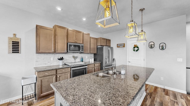 125 Bridlewood Dr, Shepherdsville, KY 40165 - kitchen featuring appliances with stainless steel finishes, a center island with sink, decorative backsplash, dark wood finished floors, and stone counters