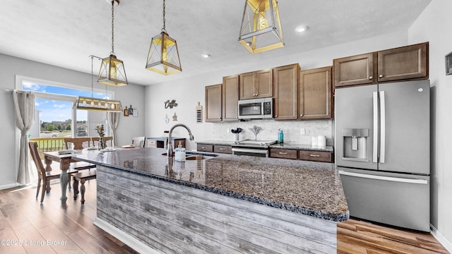 125 Bridlewood Dr, Shepherdsville, KY 40165 - kitchen with appliances with stainless steel finishes, dark wood-style floors, a center island with sink, dark stone countertops, and recessed lighting