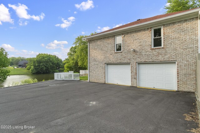 3205 Lake Pointe Ct, Crestwood, KY 40014 - view of home's exterior with asphalt driveway, a garage, brick siding, and a water view