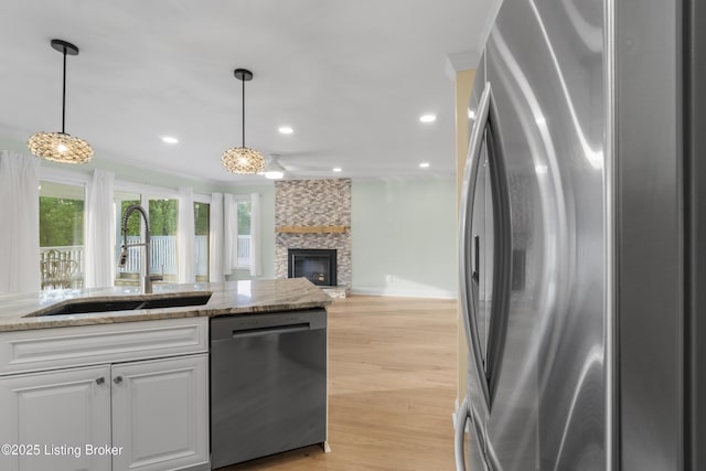 3205 Lake Pointe Ct, Crestwood, KY 40014 - kitchen with stainless steel appliances, a sink, white cabinets, light wood-style flooring, and a fireplace