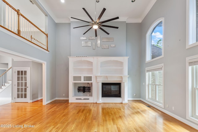 15108 Chestnut Ridge Cir, Louisville, KY 40245 - unfurnished living room with a high ceiling, light wood-style floors, a glass covered fireplace, crown molding, and stairway