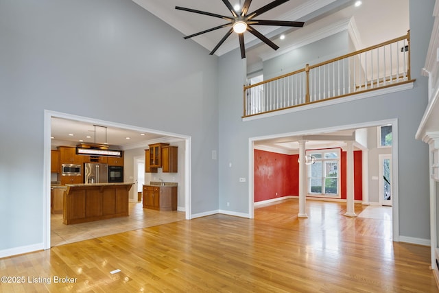 15108 Chestnut Ridge Cir, Louisville, KY 40245 - unfurnished living room with ornate columns, ornamental molding, a towering ceiling, a ceiling fan, and light wood-style flooring