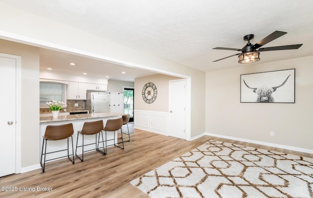 922 Fenley Ave, Louisville, KY 40222 - kitchen featuring freestanding refrigerator, a kitchen breakfast bar, ceiling fan, light wood-type flooring, and white cabinetry