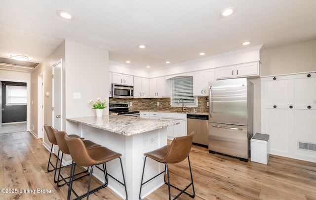 922 Fenley Ave, Louisville, KY 40222 - kitchen featuring stainless steel appliances, a breakfast bar area, light wood-style floors, white cabinets, and recessed lighting