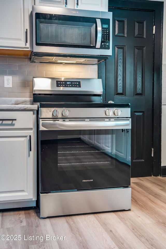 825 S 42nd St, Louisville, KY 40211 - kitchen featuring stainless steel appliances, white cabinetry, light wood-style floors, and backsplash