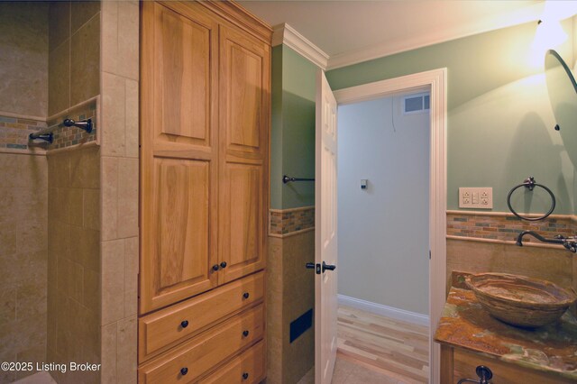 8201 Damascus Rd, Louisville, KY 40228 - bathroom with vanity, crown molding, a tile shower, a wainscoted wall, and tile walls