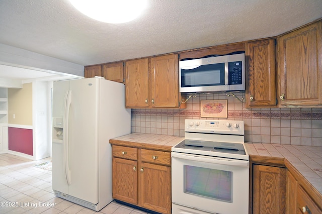 8201 Damascus Rd, Louisville, KY 40228 - kitchen featuring white appliances, tile countertops, brown cabinetry, decorative backsplash, and a textured ceiling