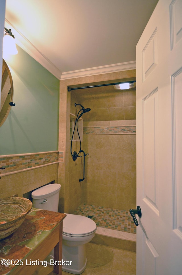 8201 Damascus Rd, Louisville, KY 40228 - bathroom featuring a shower stall, toilet, ornamental molding, tile walls, and a wainscoted wall