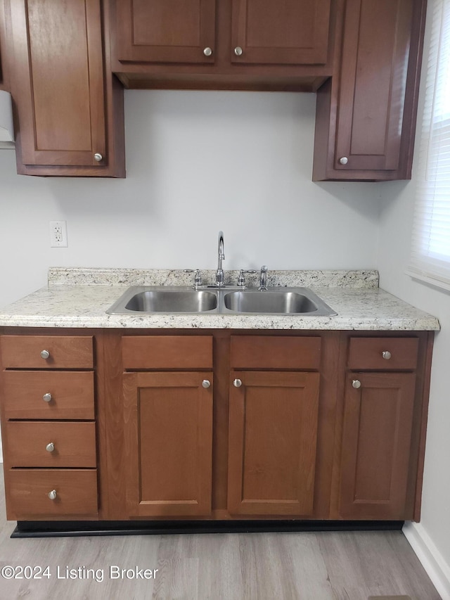 1020 Stanley Ave, Louisville, KY 40215 - kitchen featuring a sink, light wood-type flooring, brown cabinetry, and light stone counters