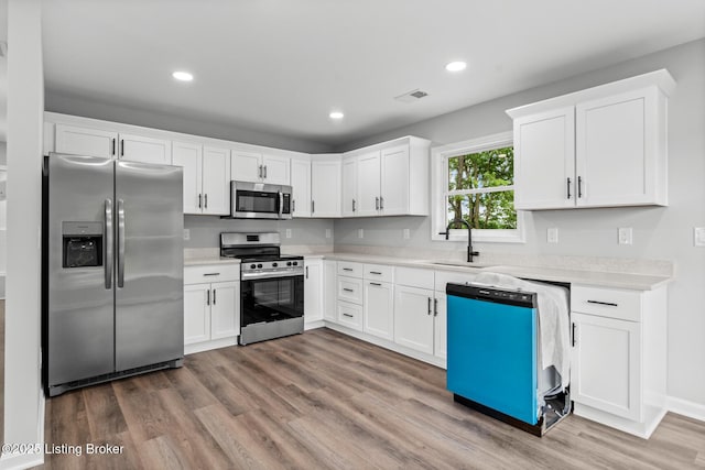 5482 Bagdad Rd, Bagdad, KY 40003 - kitchen featuring stainless steel appliances, a sink, light countertops, wood finished floors, and white cabinets