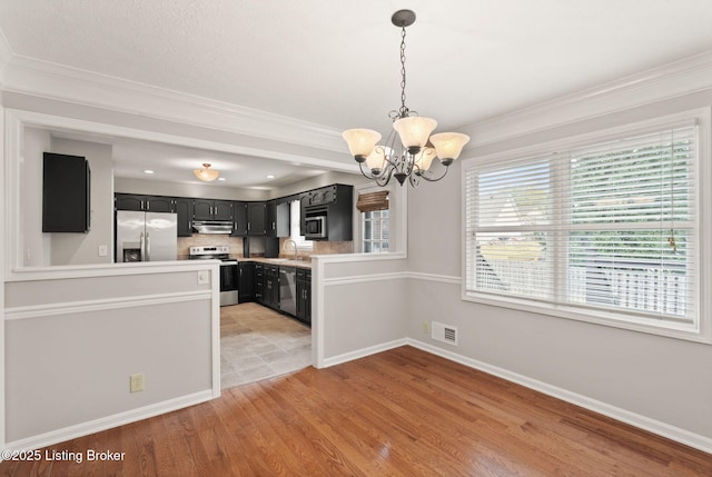 12409 Ledges Dr, Louisville, KY 40243 - kitchen with appliances with stainless steel finishes, a chandelier, under cabinet range hood, light wood-style floors, and baseboards