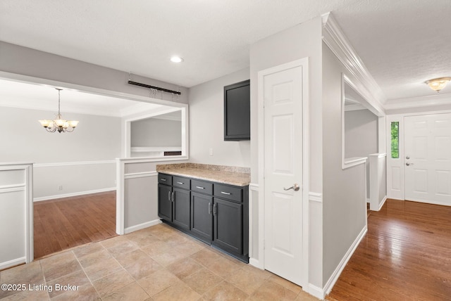 12409 Ledges Dr, Louisville, KY 40243 - kitchen with a chandelier, ornamental molding, light countertops, dark cabinets, and light wood-style floors