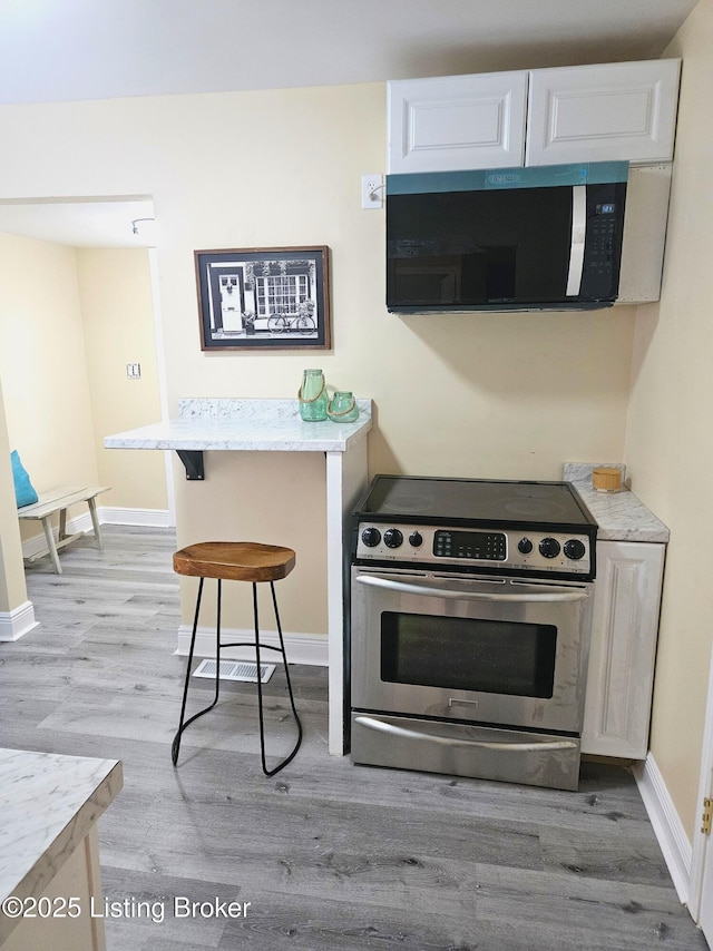 1165 Lincoln Ave, Louisville, KY 40208 - kitchen with electric stove, light wood-style floors, light countertops, and baseboards