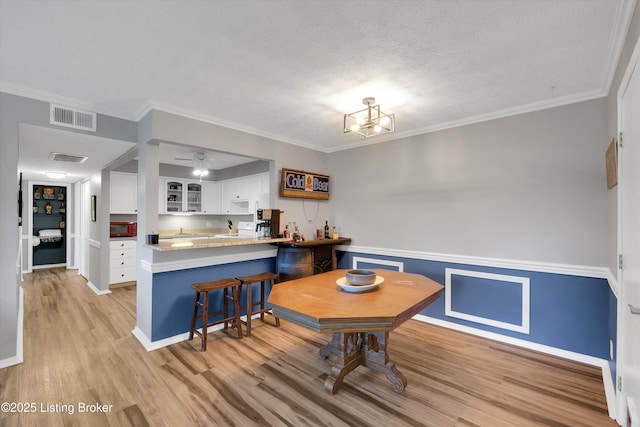 1008 Lake Way Unit D12, Louisville, KY 40222 - dining room with light wood-style flooring, wainscoting, crown molding, a textured ceiling, and baseboards