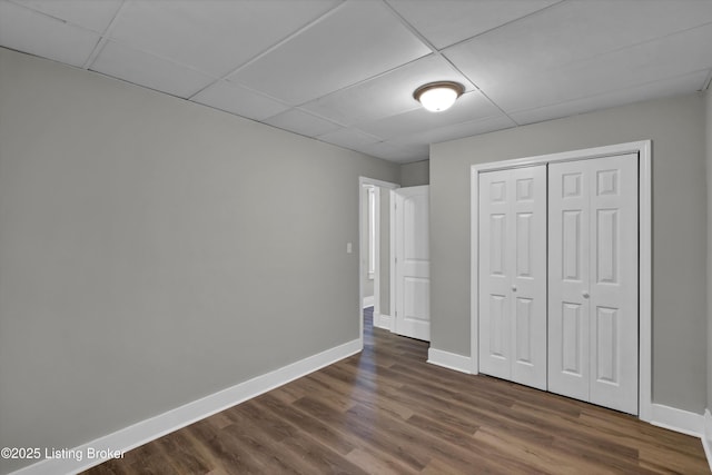 209 W Kenton St, Louisville, KY 40214 - unfurnished bedroom featuring a drop ceiling, baseboards, dark wood-style flooring, and a closet