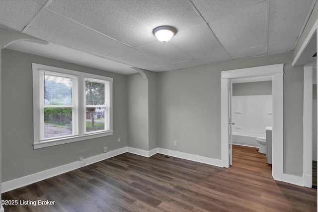 209 W Kenton St, Louisville, KY 40214 - unfurnished room with a drop ceiling, dark wood-style flooring, baseboards, and arched walkways