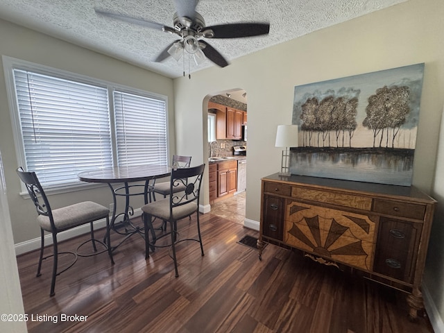 1236 Carrico Ave, Louisville, KY 40215 - dining space featuring arched walkways, dark wood-style floors, ceiling fan, baseboards, and a textured ceiling