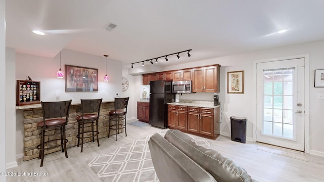 150 E Laurel River Drive Rd, Shepherdsville, KY 40165 - kitchen with freestanding refrigerator, stainless steel microwave, a breakfast bar, light wood-type flooring, and rail lighting