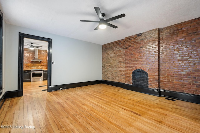 965 S Shelby St, Louisville, KY 40203 - unfurnished living room with a brick fireplace, a ceiling fan, light wood finished floors, brick wall, and baseboards