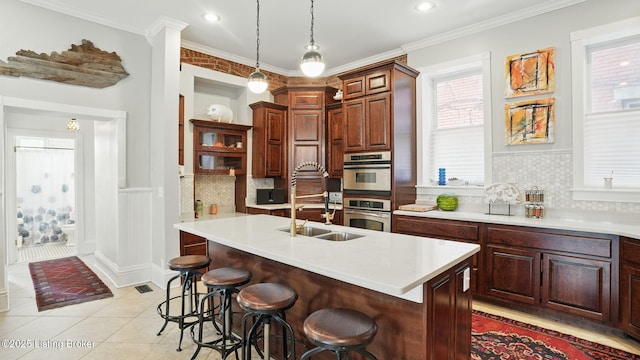 1212 S 2nd St, Louisville, KY 40203 - kitchen featuring light countertops, a breakfast bar area, backsplash, light tile patterned flooring, and hanging light fixtures