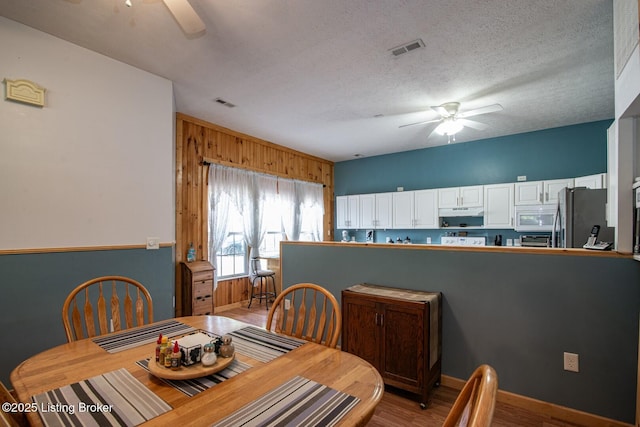 201 Wildflower Ln, Big Springs, KY 40175 - dining space featuring ceiling fan, light wood-style flooring, wooden walls, and a textured ceiling