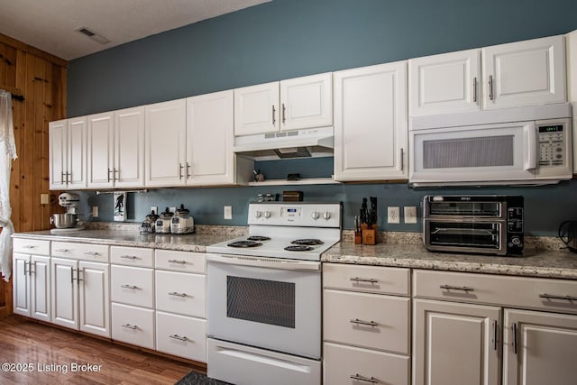 201 Wildflower Ln, Big Springs, KY 40175 - kitchen with white appliances, under cabinet range hood, white cabinets, wooden walls, and dark wood-style flooring