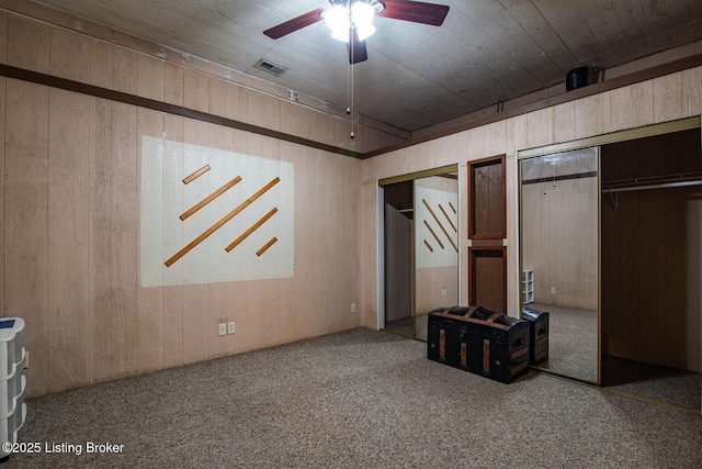 201 Wildflower Ln, Big Springs, KY 40175 - unfurnished bedroom featuring multiple closets, wooden walls, carpet floors, and a ceiling fan