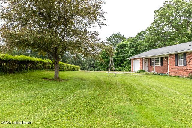 3110 Mount Lebanon Rd, Charlestown, IN 47111 - view of green lawn with an attached garage and view of wooded area