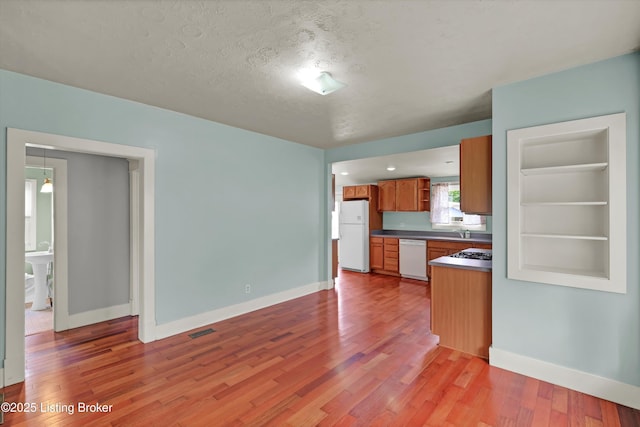 3707 Lentz Ave, Louisville, KY 40215 - kitchen featuring white appliances, dark countertops, light wood-style flooring, baseboards, and brown cabinetry