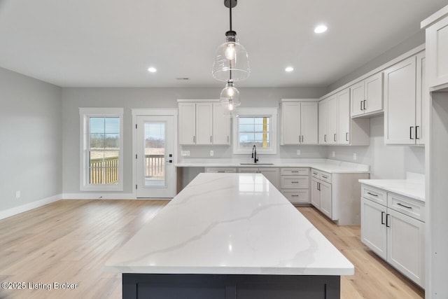 488 Capps Rd, Campbellsville, KY 42718 - kitchen featuring a sink, a kitchen island, light stone countertops, light wood-type flooring, and hanging light fixtures