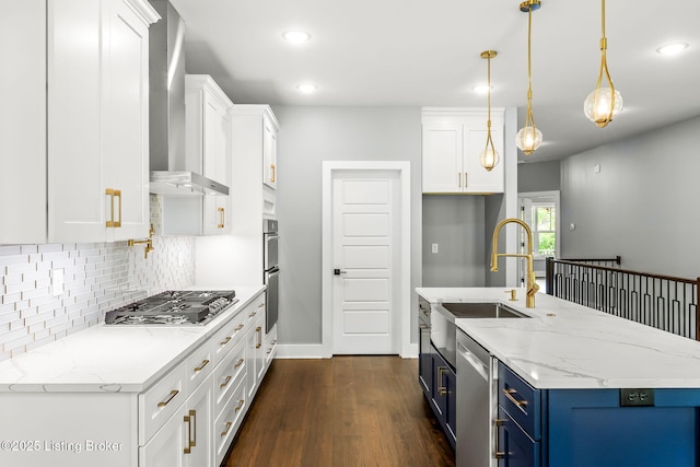 912 Artisan Pkwy, La Grange, KY 40031 - kitchen with blue cabinetry, wall chimney exhaust hood, appliances with stainless steel finishes, a sink, and backsplash
