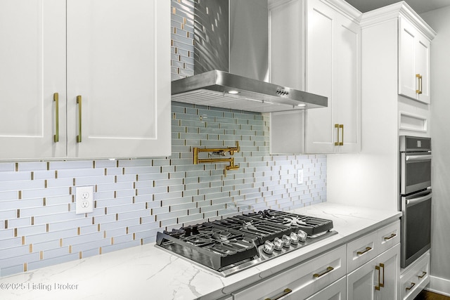 912 Artisan Pkwy, La Grange, KY 40031 - kitchen with wall chimney range hood, stainless steel appliances, white cabinetry, decorative backsplash, and light stone counters