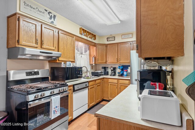 1261 Lipps Ln, Louisville, KY 40219 - kitchen with stainless steel gas stove, under cabinet range hood, a sink, white dishwasher, and light countertops